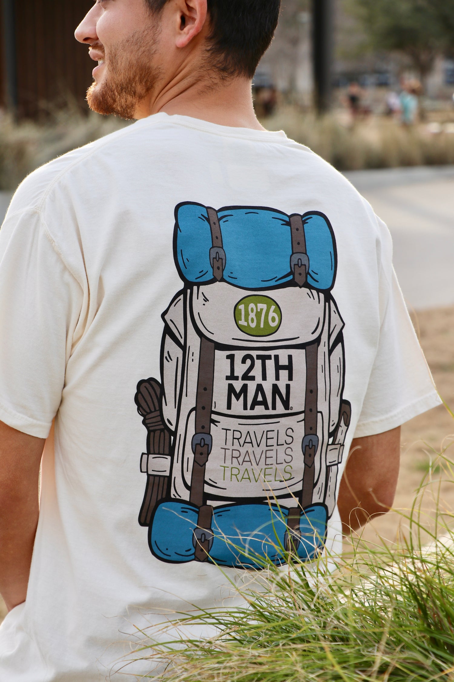 White back of a t-shirt with a blue camping backpack and "12th man" in black.