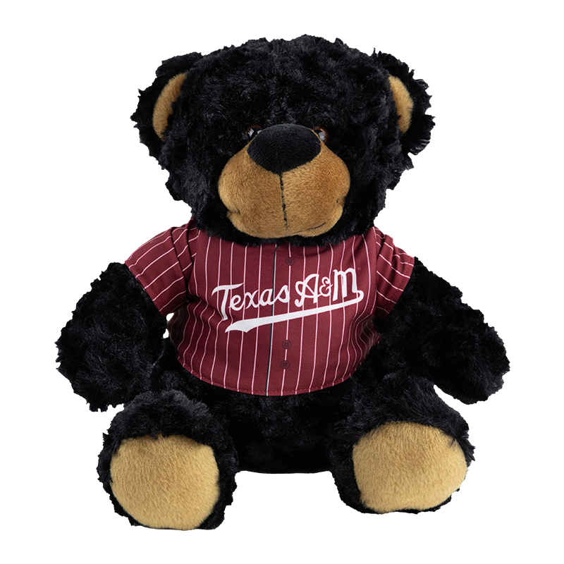 A black teddy bear wearing a maroon and white striped baseball jersey with 'Texas A&M' written across the chest