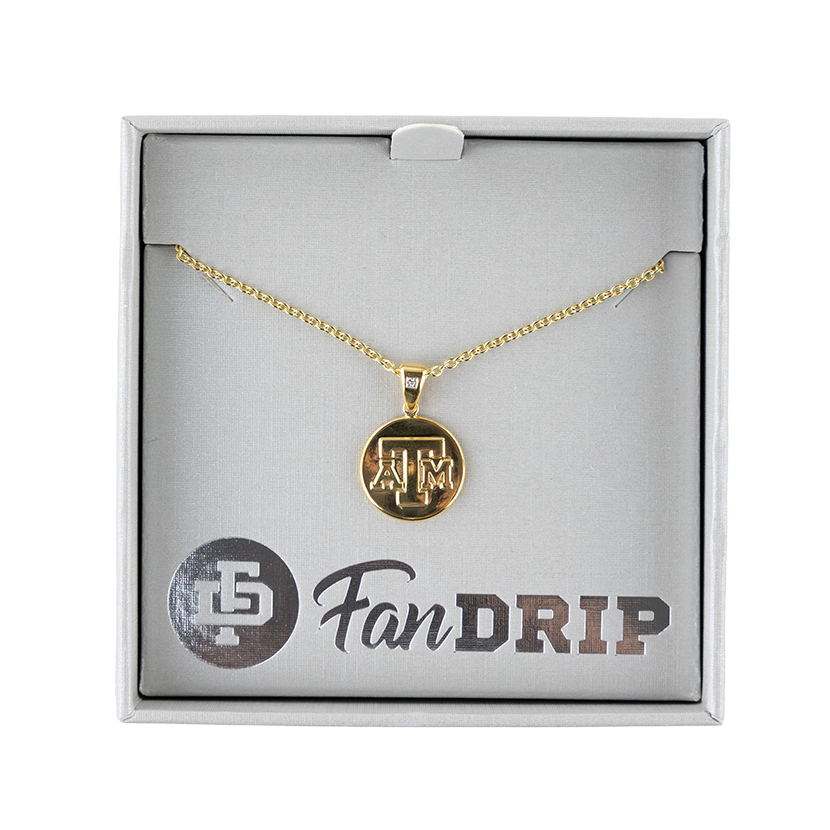 A gold necklace with a gold circular pendant. The pendant has A&M printed in raised gold block letters. 